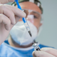 Doctor places syringe in bottle of vaccine